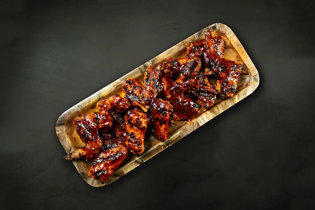 A tray of 12 grilled peri peri chicken wings served on seasoned rice