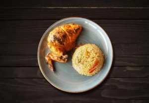 1/4 flame-grilled chicken breast and wing with fries and corn on a plate